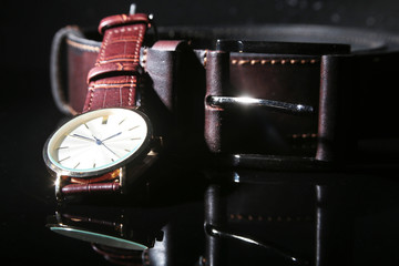 Men's accessories with brown leather wallet, belt and watch.