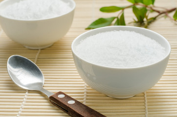 Salt in a white bowl on bamboo background.