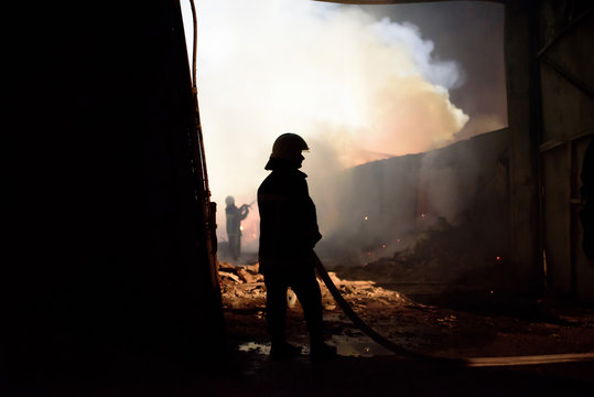 Silhouette of fireman fighting bushfire at night
