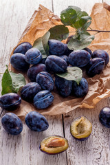 Fresh plums with leaves on wooden table.