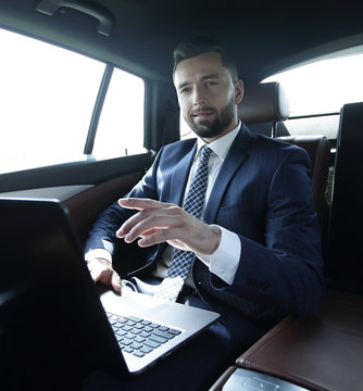 businessman sitting in the back seat in the car and pointing his finger forward