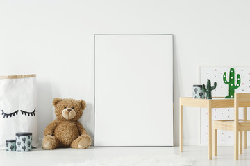 Mockup poster, teddy bear and material basket placed on the floor in white room interior with...