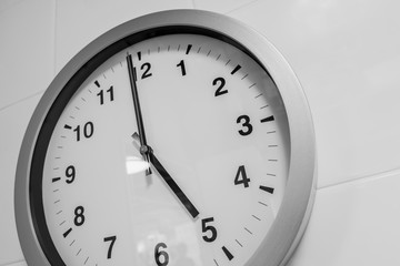 closeup simple clock on white wall time at 5 o'clock