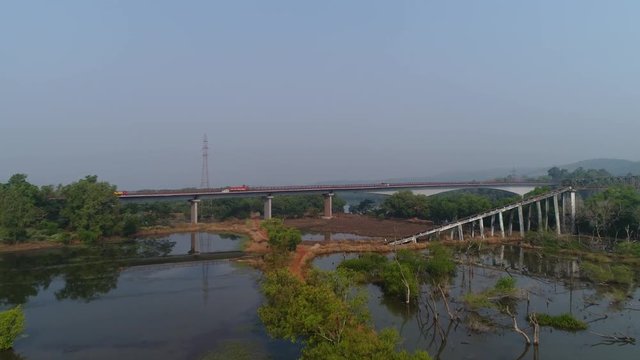 Aerial view. Flying over beautiful landscape a large automobile bridge over the river, on which cars ride. Beautiful reflection in the water. 