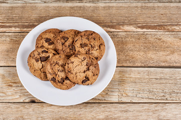 oatmeal cookies with chocolate slices in a white plate on a wooden background