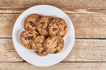 oatmeal cookies with chocolate slices in a white plate on a wooden background