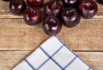 red plums next to a doily on a wooden background
