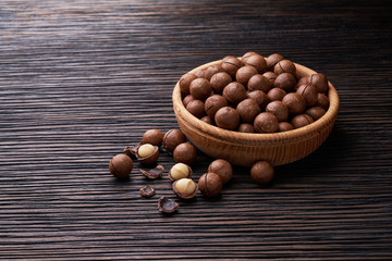 Macadamia nuts in wooden bowl   on brown wooden table
