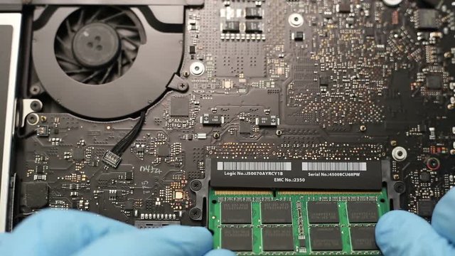 Hands installing RAM memory.