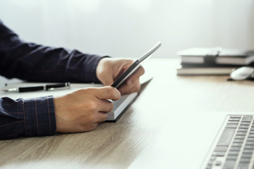 close up hands of man touching tablet, multitasking on screen in an office