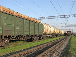 Fototapeta na wymiar Railway junction. Cargo transportation by rail. Trains with tanks with oil and fuel. In the foreground is a container with timber.