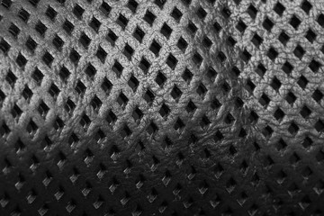 Natural black leather with perforation in form of the rhombus close-up. Background