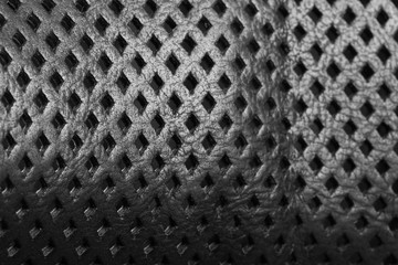Natural black leather with perforation in form of the rhombus close-up. Background