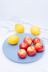 Fresh apples and lemons in a plate on white background.
