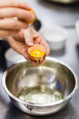 the cook breaks the egg in a steel bowl - 212045226