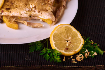 delicious roasted carp fish with lemon slices, spices, and fresh rosemary on white plate, view from above, close-up