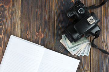 Camera, notebook and field flowers on dark wooden background. Freelance. Earnings in the photo.