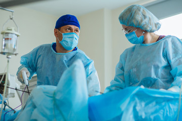 Male surgeon's holing the instrument in abdomen of patient. Female assistant help him. The surgeon's doing laparoscopic surgery in the operating room. Minimally invasive surgery. Close up