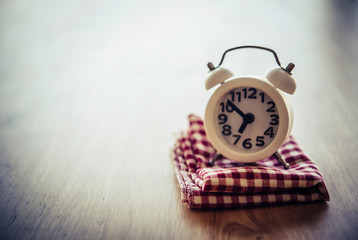 White alarm clock and handkerchief on white table