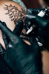 cropped shot of tattooing process on shoulder in salon