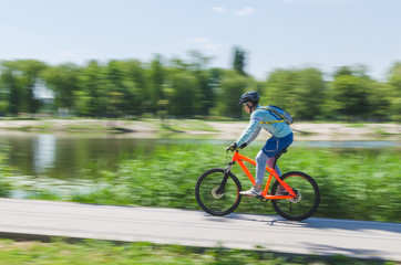 A cyclist in a helmet rides a bicycle path, motion blur