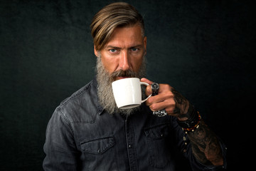 Porträt eines bärtigen Mannes mit einem Tasse Kaffee, vor dunklem Hintergrund