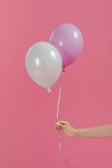 Cropped view of woman holding two balloons isolated on pink