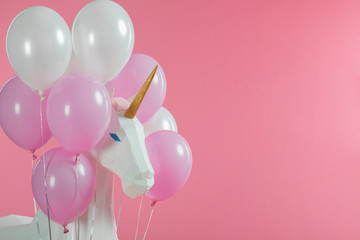 Toy unicorn among pink and white balloons isolated on pink © LIGHTFIELD STUDIOS