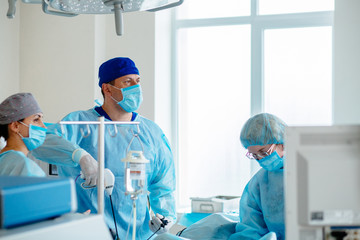 Surgeons team preforming operation in hospital operating theater, male surgeon operating...