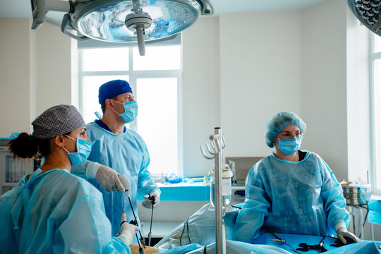 Surgeons team preforming operation in hospital operating theater, male surgeon operating patient,wearing surgical gown,operating room,,working with surgical laparoscopy instruments. Gynecology.
