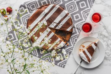 top view of delicious homemade cake, fresh strawberries and white flowers