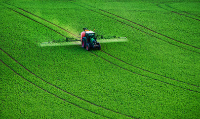 Farm machinery spraying insecticide to the green field, agricultural natural seasonal spring...