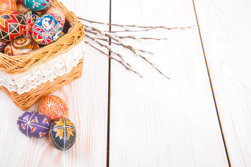 Obraz premium Easter eggs in a basket on white plank background.