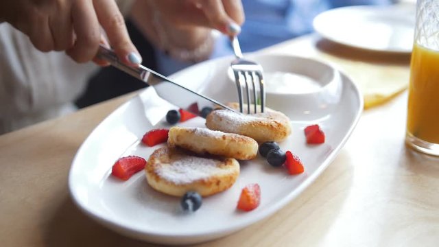 Girl eating cottage cheescakes during breakfast in the cafe