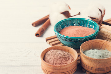 Red and blue cosmetic moroccan clay powder, spa composition with lit candle on white background