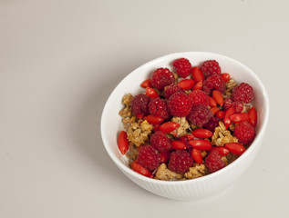 Bowl with cereals and fresh raspberries and goji berry