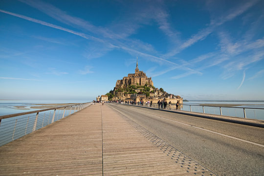 Road to amazing Mont Saint Michel abbey. Tourists are going to the abbey.  It is one of the most famous tourist attractions in France. Landscape photo during sunrise. Normandy, France