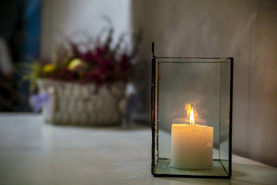 A burning candle in a glass cube.