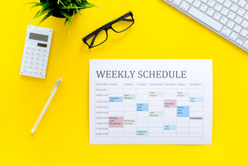 Weekly schedule of manager, office worker, pr specialist or marketing expert. Table with multicolored blocks on yellow office desk with computer, glasses, calculator top view