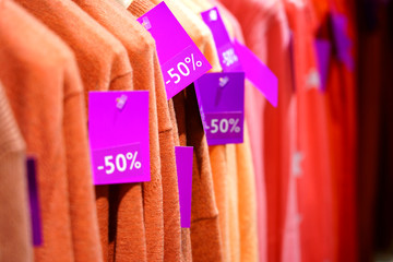 Labels showing marked down price percentages on clothes during a sale