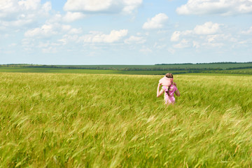Naklejka na ściany i meble child walking through the wheat field, bright sun, beautiful summer landscape
