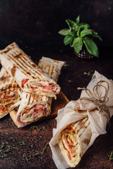 Shawarma Sandwich - a fresh roll of thin lavash, filled with grilled meat, mushrooms, cheese and herbs. Oriental snack. On a metal background.