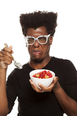 disgusted young handsome afro american guy hipster eating cereals woth fresh fruits isolated on...