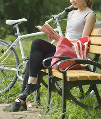 ベンチに座って本を読む女性