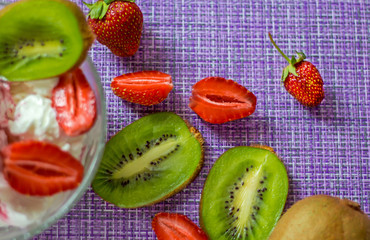 strawberry and kiwi berries on a purple napkin with dessert