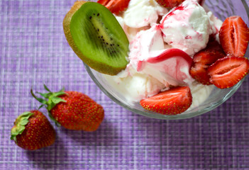 strawberry and kiwi berries on a purple napkin with dessert