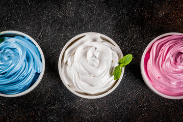 Healthy diet summer dessert, vanilla and berry frozen yogurt or  soft ice cream in white bowls, white marble background copy space above