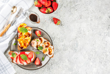 Healthy summer breakfast snack, Rye toast sandwiches with fruit and berries - strawberry, peach, banana - with chocolate sauce, light concrete background copy space