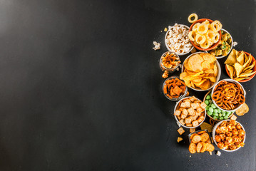 Variation different unhealthy snacks crackers, sweet salted popcorn, tortillas, nuts, straws, bretsels, back chalkboard copy space