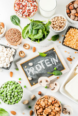 Healthy diet vegan food, veggie protein sources: Tofu, vegan milk, beans, lentils, nuts, soy milk, spinach and seeds. Top view on white table.